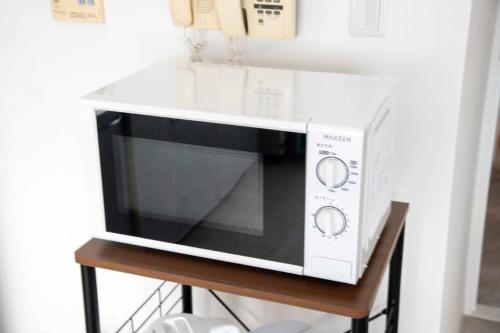 a microwave oven sitting on a wooden stand at 横須賀アロハハウス702 in Yokosuka