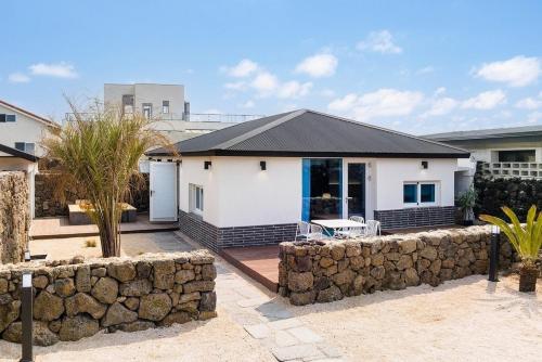 a white house with a stone wall at Jeju Slow Stay in Jeju