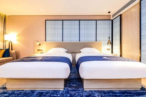 two beds in a bedroom with a large window at Echarm Hotel Xingyi Menglecheng Kratie Plaza in Xingyin Wanfenglin Airport