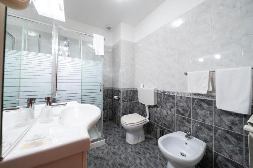 a white bathroom with a sink and a toilet at Hotel Cavour Resort in Moncalieri