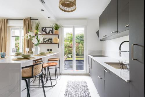 une cuisine avec comptoirs et tabourets blancs dans l'établissement La Villa Nova Pomponne - 3 chambres et jardin, à Magny-le-Hongre