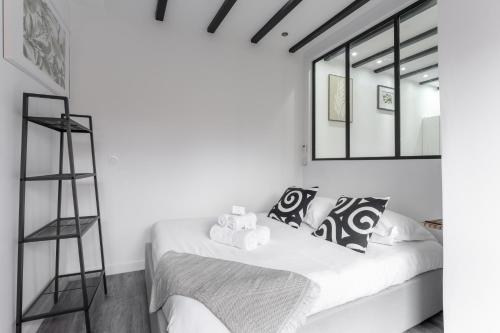 a white bedroom with a bed and a mirror at Le Petit Enclos - Appt climatisé parking privé in Vaulx-en-Velin