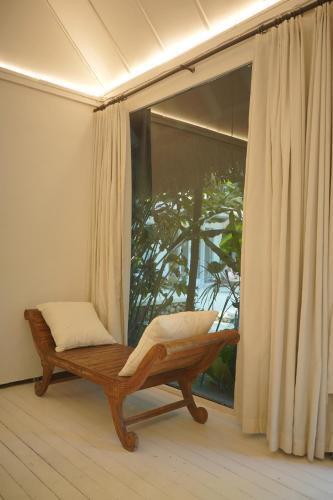una panchina seduta davanti a una grande finestra di Joy Canggu a Canggu