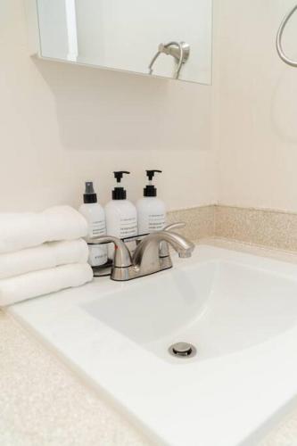 a bathroom sink with three bottles of soap and towels at Chez Alphonse in Seattle