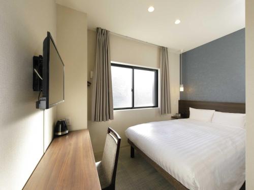 a bedroom with a bed and a desk and a window at Smart Place Inn Kyoto Shijo Omiya Station in Kyoto