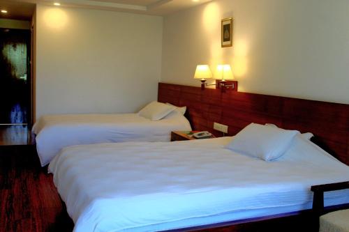two beds in a hotel room with white sheets at Lumbini Hotel Kasai in Lumbini