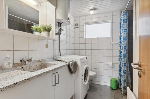 a bathroom with a washing machine and a sink at Feriehus 1086 in Ulfborg