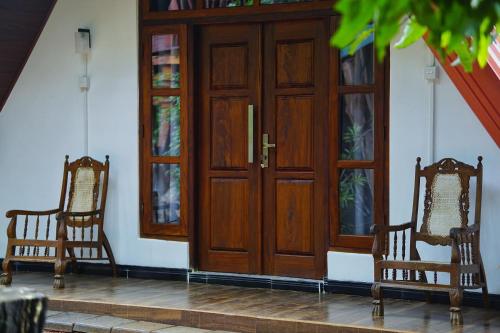 two chairs sitting in front of a wooden door at Sky Villa Sigiriya in Sigiriya