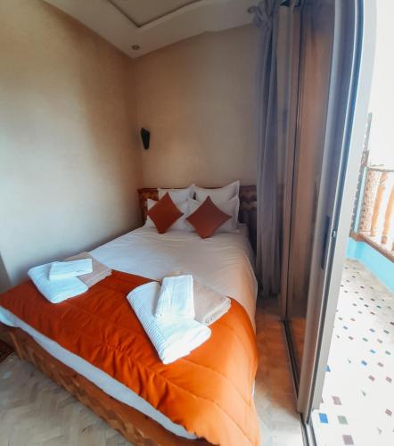 a bedroom with a large bed with orange sheets and pillows at Imsouane WOOD HOUSE in Imsouane