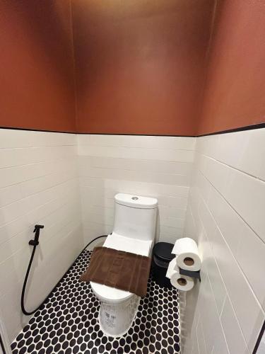 a bathroom with a toilet with a black and white tile floor at Brix26 in Bangkok