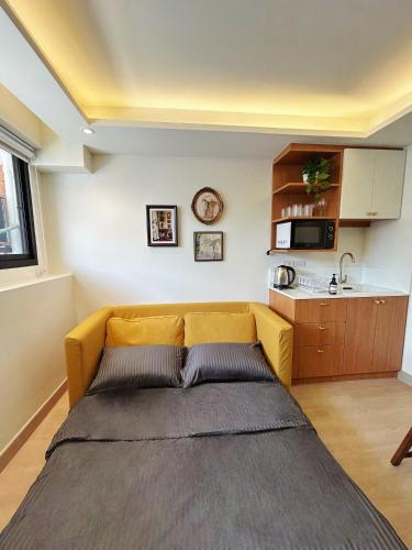 a yellow couch in a room with a kitchen at Brix26 in Bangkok