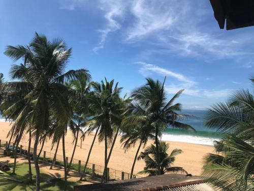 a view of a beach with palm trees and the ocean at PRANA Beach Hotel Hikkaduwa in Hikkaduwa