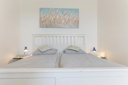 a white bedroom with two beds and two lamps at "Ferienhof Sporleder" - Bauernhaus 2 in Meeschendorf