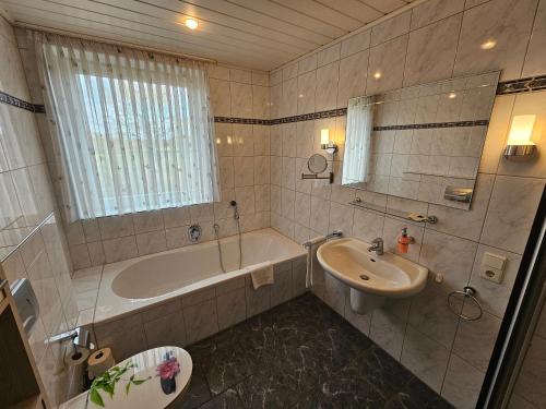 a bathroom with a tub and a sink and a bath tub at Gästehaus Grunewald Bed & Breakfast in Heiden