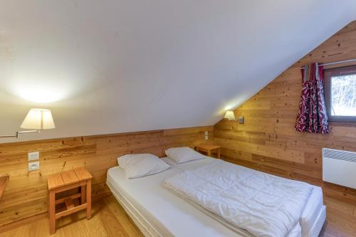 a bedroom with a white bed and wooden walls at Chalet le Regain in Villard-Reculas