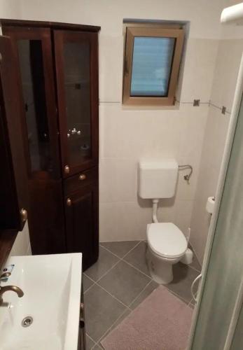 a bathroom with a toilet and a sink and a window at Apartments and Rooms Frane in Palit