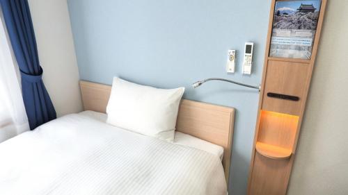a small bedroom with a bed and a lamp at Toyoko Inn Takamatsu Ekimae in Takamatsu