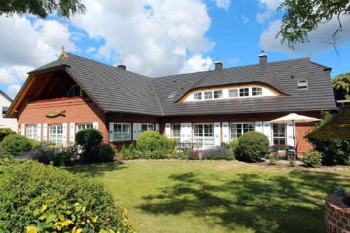 a house with a black roof and a yard at Ferienwohnungen unterm Reetdach m Terras o Balk u Sauna in Middelhagen