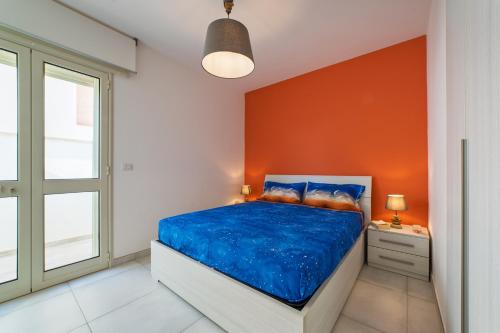 Un dormitorio con una pared de acento naranja y una cama en Dimora da mare, en Marina di Pescoluse