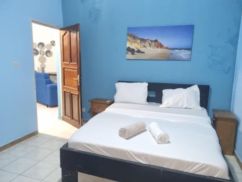 a blue bedroom with a bed with two rolled towels on it at VINCE SALY 3 in Sali Nianiaral