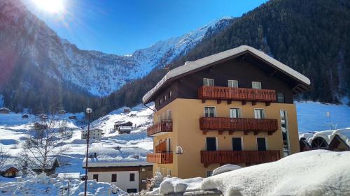 a building with snow on the ground next to a mountain at Casa vacanze Heidi e Peter Val di Rabbi in Rabbi