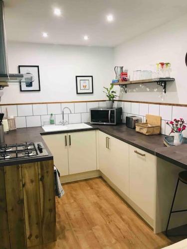 a kitchen with white cabinets and a counter top at Hot tub - Number 37 in Llansantffraid Glan Conwy