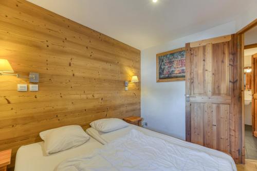 a bed in a room with a wooden wall at Chalet le Regain in Villard-Reculas