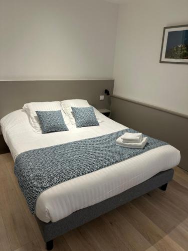 a bed with two blue pillows on top of it at Logis Hôtel du Fer à Cheval in Yenne