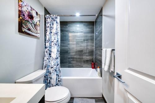 a bathroom with a toilet and a tub and a sink at RivetStays - The Jarvis in Toronto