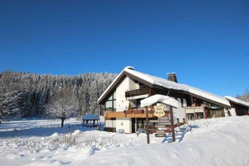 une cabane en rondins avec de la neige sur le toit dans l'établissement Gästehaus Seewald- Ferienwohnung 1 "Ahorn", Schluchsee, Blasiwald, à Schluchsee
