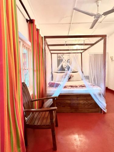 a bedroom with a canopy bed and a chair at Villa Sunny Days in Hikkaduwa