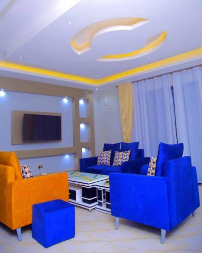 a living room with blue couches and a tv at Crown Elegance Suites in Kampala