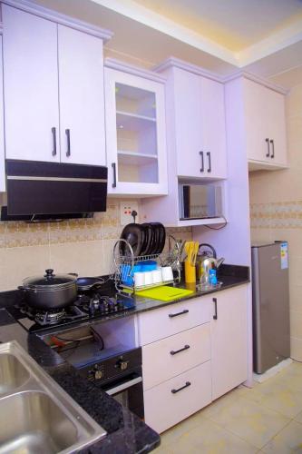 a kitchen with white cabinets and a stove top oven at Crown Elegance Suites in Kampala