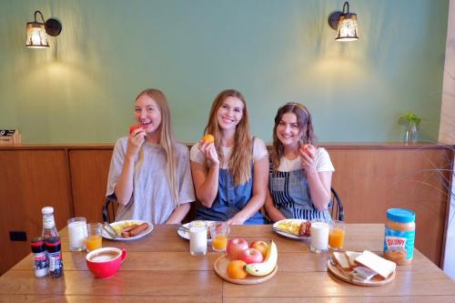 three girls sitting at a table eating food at Red Panda Hostel & Cafe in Chiang Mai