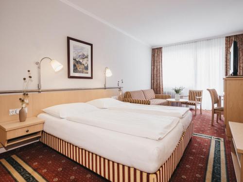 a bedroom with a large bed and a living room at Sporthotel Royer in Schladming