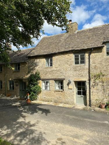an old stone house with a green door at Cosy Cotswold Cottage in Stow on the Wold