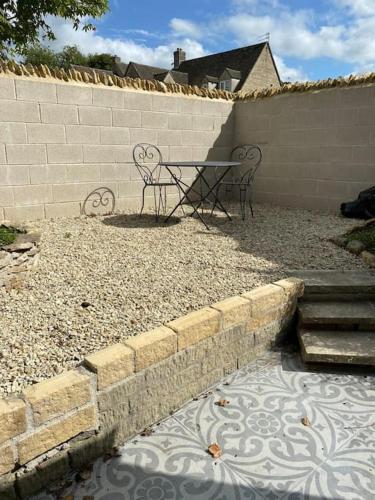 a patio with a table and chairs next to a wall at Cosy Cotswold Cottage in Stow on the Wold
