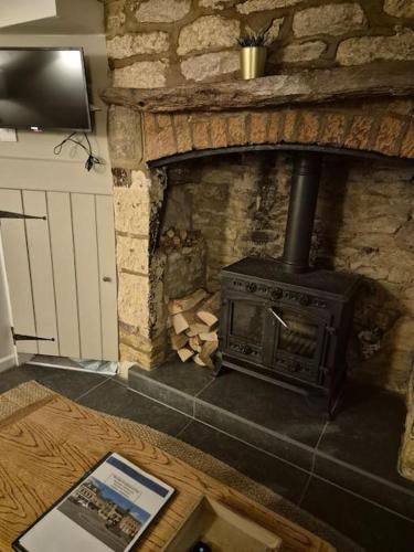 a stone fireplace with a stove in a room at Cosy Cotswold Cottage in Stow on the Wold