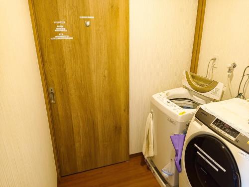 a kitchen with a washing machine and a wooden door at Guest House Ihatov - Vacation STAY 22122v in Takamatsu
