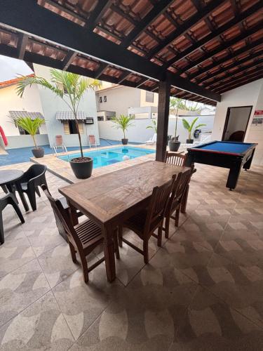 a wooden table and chairs in a patio with a pool at Casa no Condomínio CenterVille in Bertioga