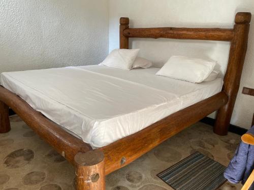 a wooden bed with white sheets and pillows on it at Kandy Food Lovers Home Stay by AGS in Kandy