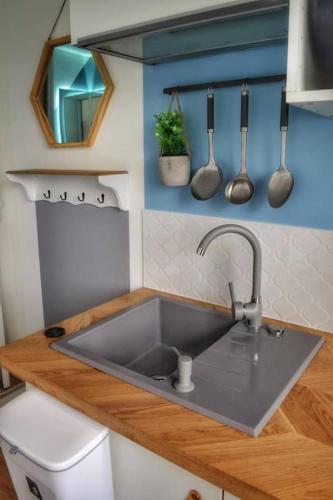 - une cuisine avec évier et ustensiles sur le mur dans l'établissement Le Cosy - Petit studio douillet proche de la gare, à Juvisy-sur-Orge