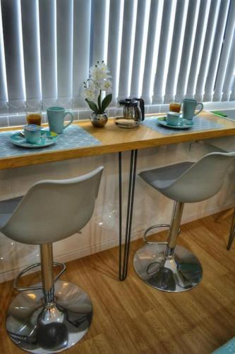 une table en bois avec deux chaises et une table avec des tasses et des boissons dans l'établissement Le Cosy - Petit studio douillet proche de la gare, à Juvisy-sur-Orge
