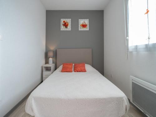 - une chambre avec un lit blanc et deux oreillers orange dans l'établissement La Dune 16 - Villa 3P6, à Sérignan