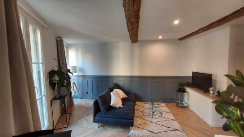 a living room with a blue couch and a tv at Appartement des Augustins in Aix-en-Provence