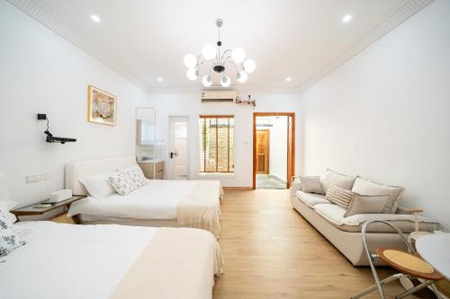 a white room with two beds and a couch at Tonight Homestay West Nanjing Road Shanghai in Shanghai