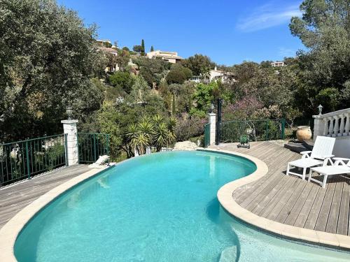 une grande piscine avec une terrasse en bois et 2 chaises dans l'établissement Villa Cigalou pour 8 personnes avec piscine chauffée et petite vue mer au domaine de Valcros à La Londe les Maures, à La Londe-les-Maures