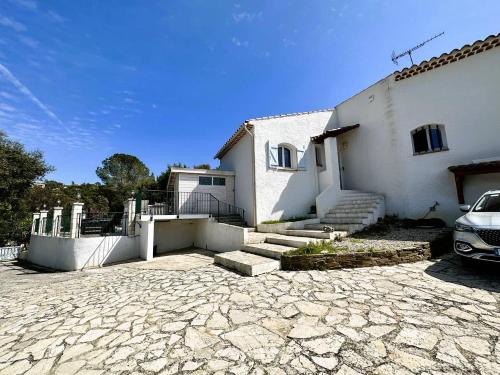 une maison blanche avec une voiture garée devant elle dans l'établissement Villa Cigalou pour 8 personnes avec piscine chauffée et petite vue mer au domaine de Valcros à La Londe les Maures, à La Londe-les-Maures