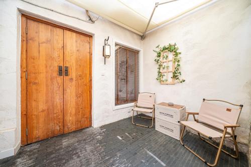 a room with two chairs and a wooden door at Tonight Homestay West Nanjing Road Shanghai in Shanghai