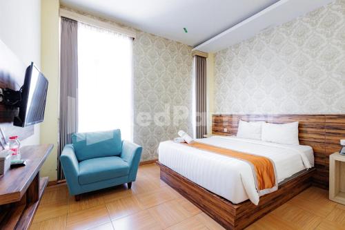 a bedroom with a bed and a blue chair at De Malang Sweet Homestay Syariah Mitra RedDoorz in Malang